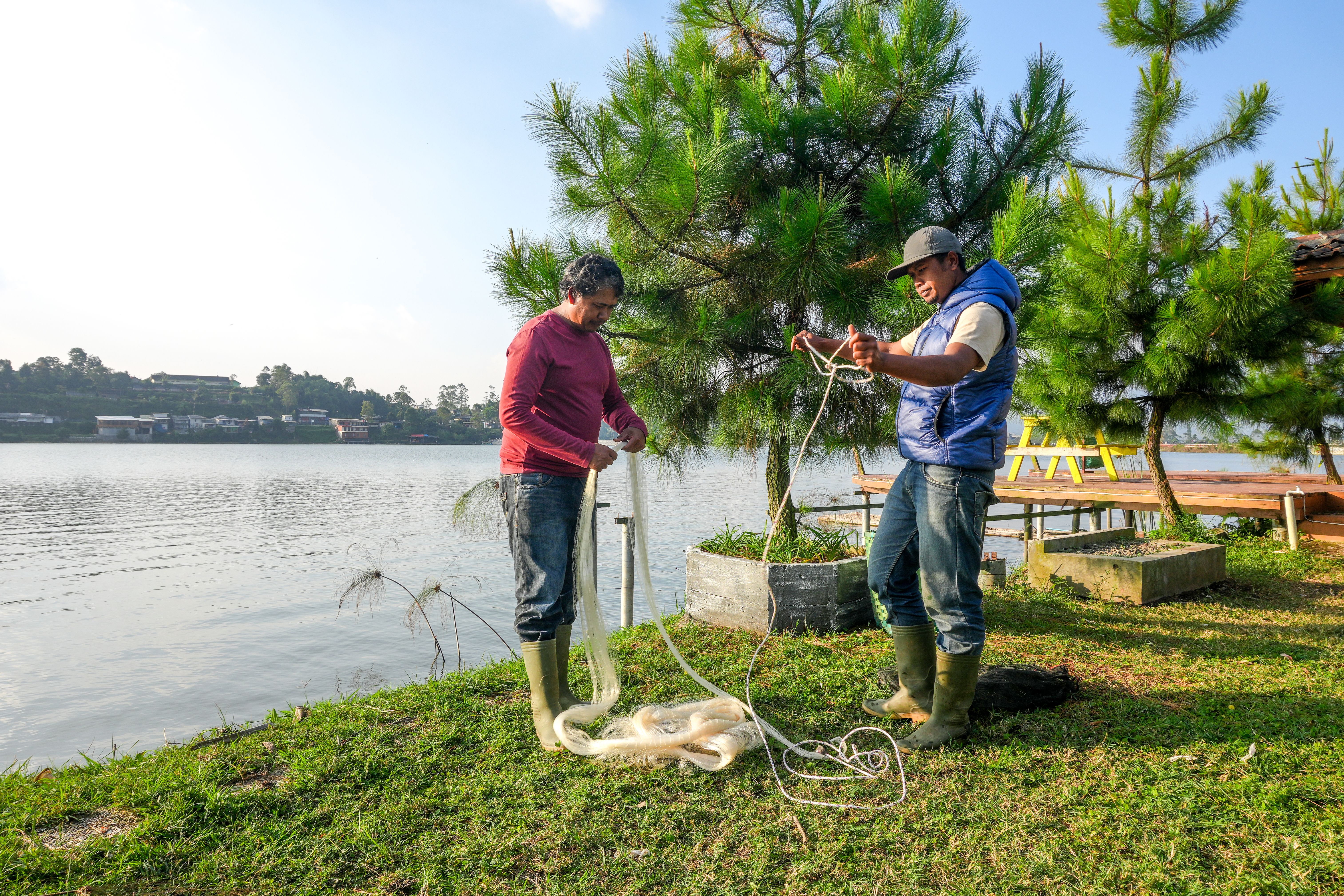 two-men-stand-by-lake-carefully-unraveling-fishing-net-as-they-prepare-their-daily-work.jpg
