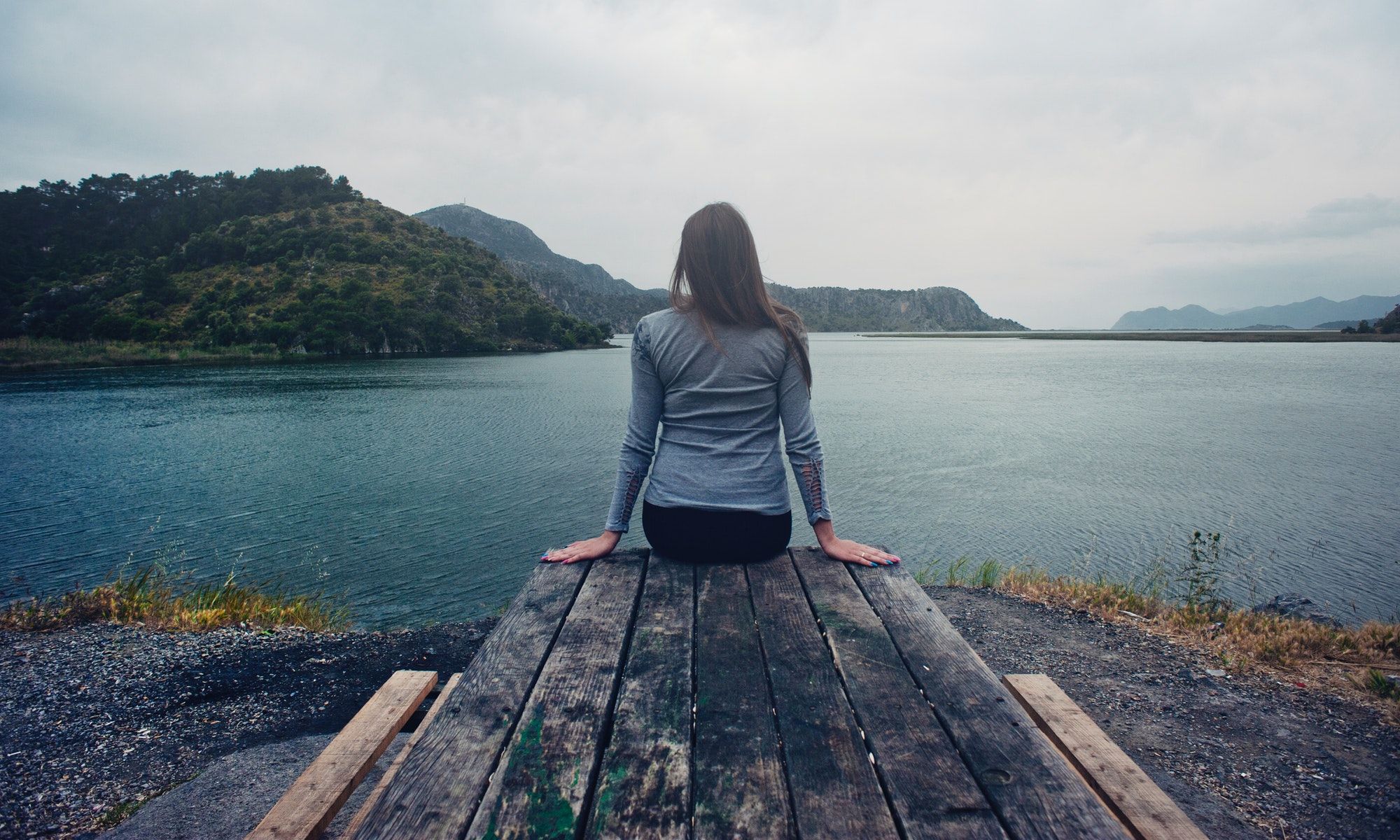 woman sitting on a wooden ledge facing the lake