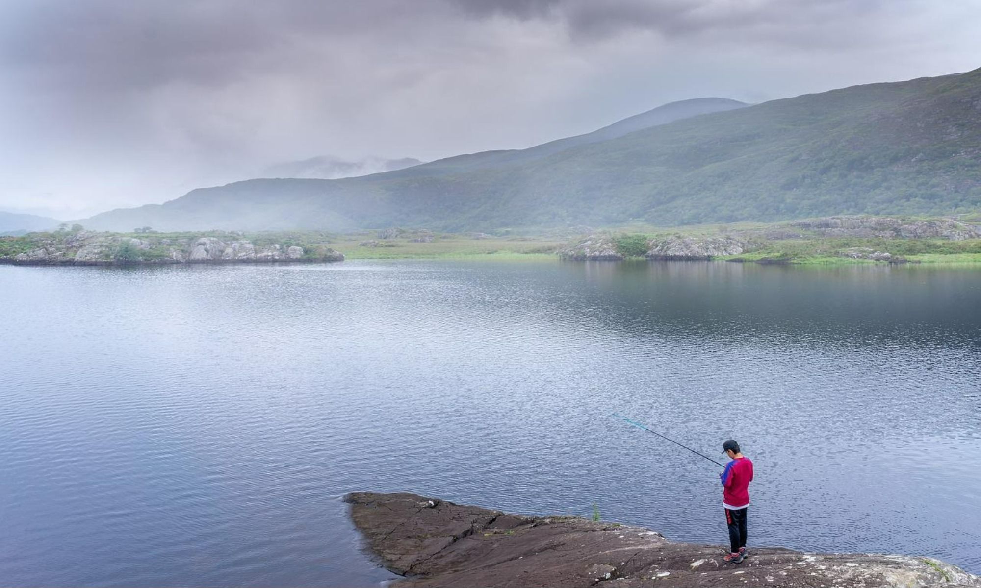 an angler standing on a jetty and fishing by the water body