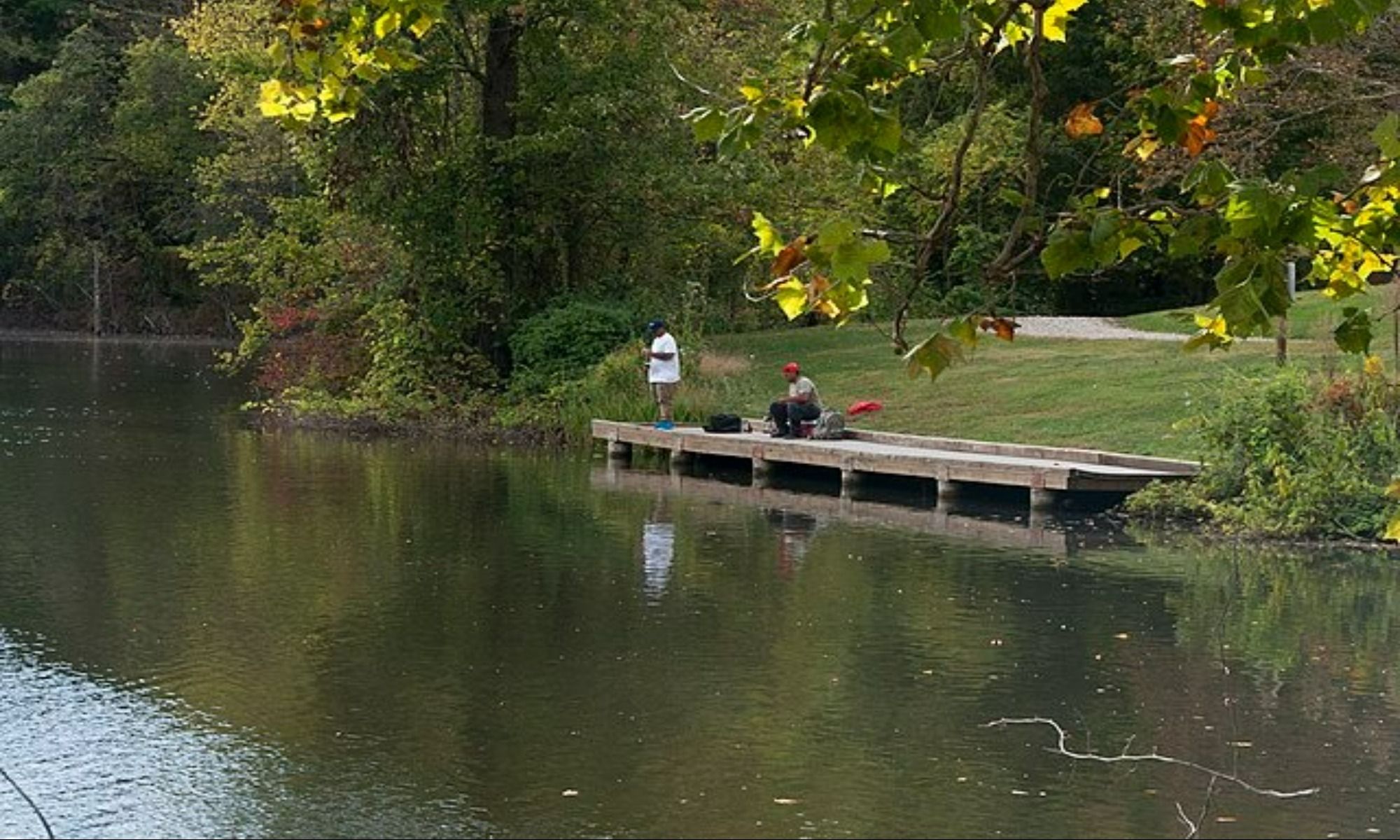 two men on the dock fishing by the creek