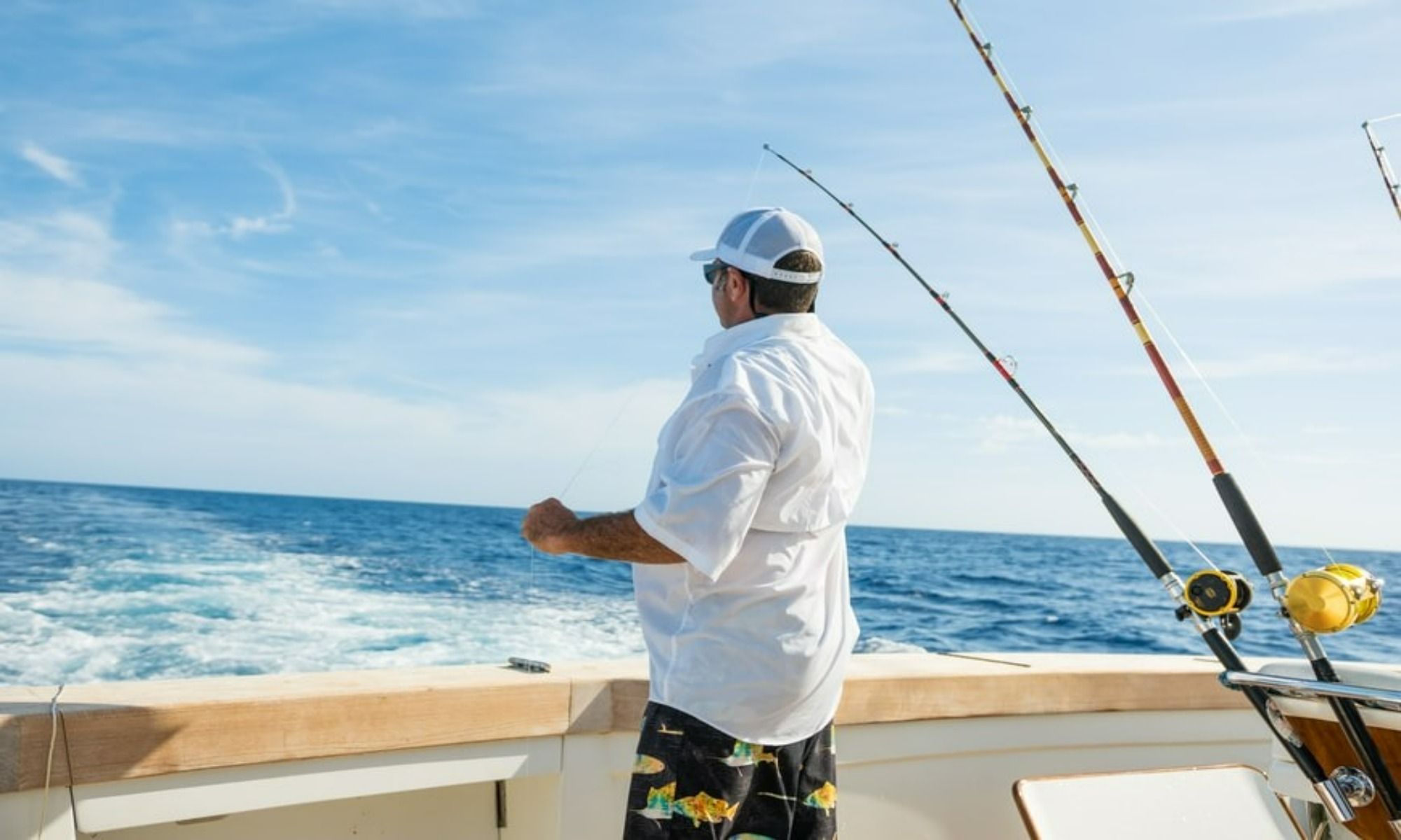 Man standing on a boat with fishing rods behind him