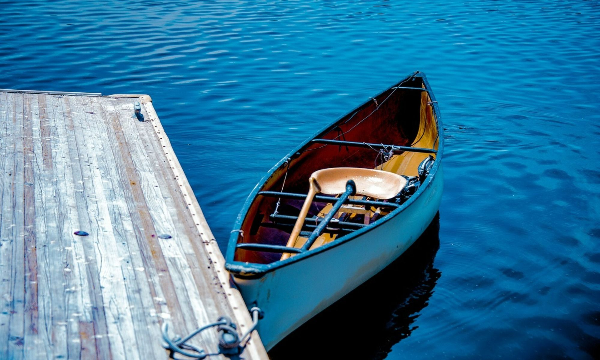 small blue boat tied on a wooden dock