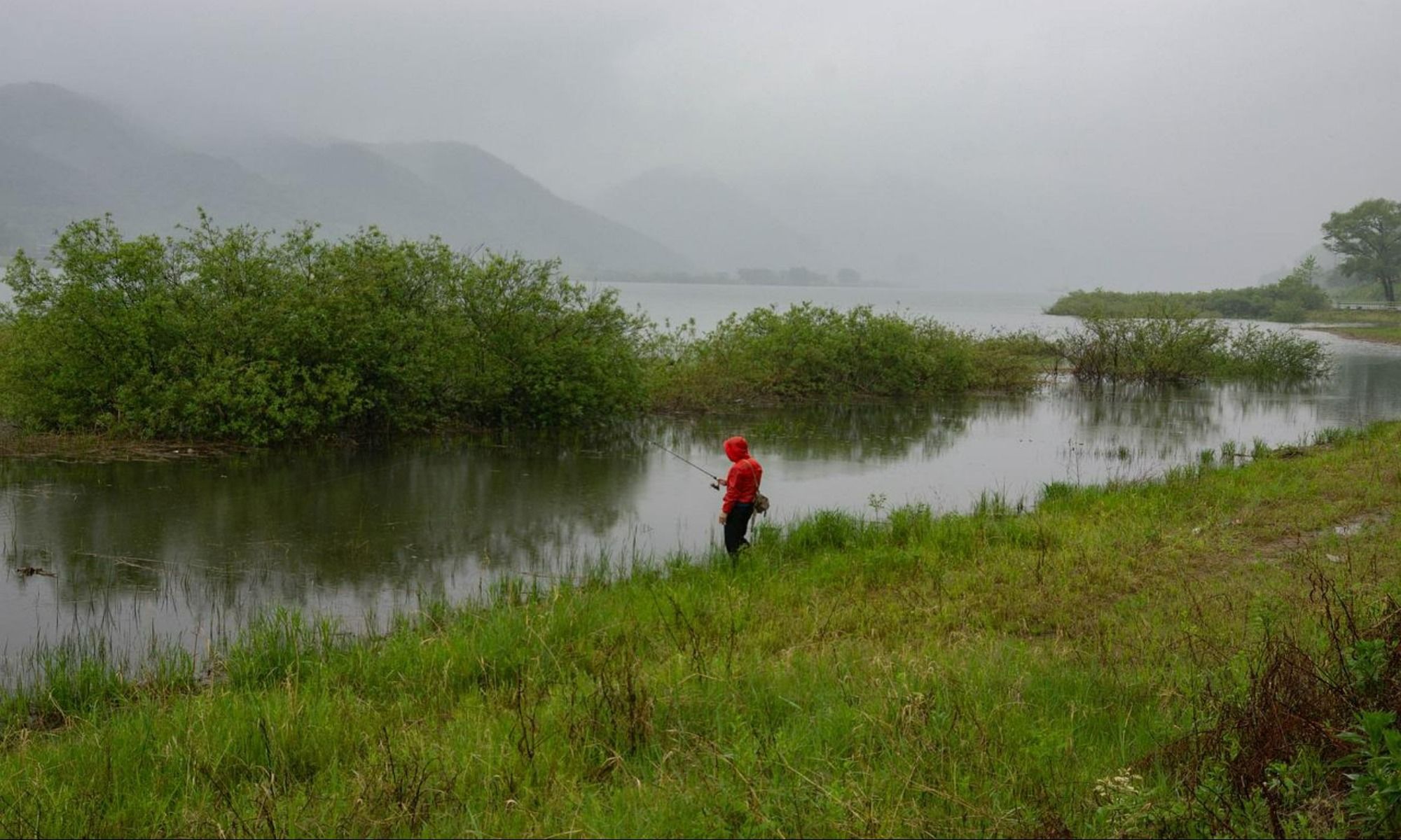 angler by the lake fishing on a red jacket